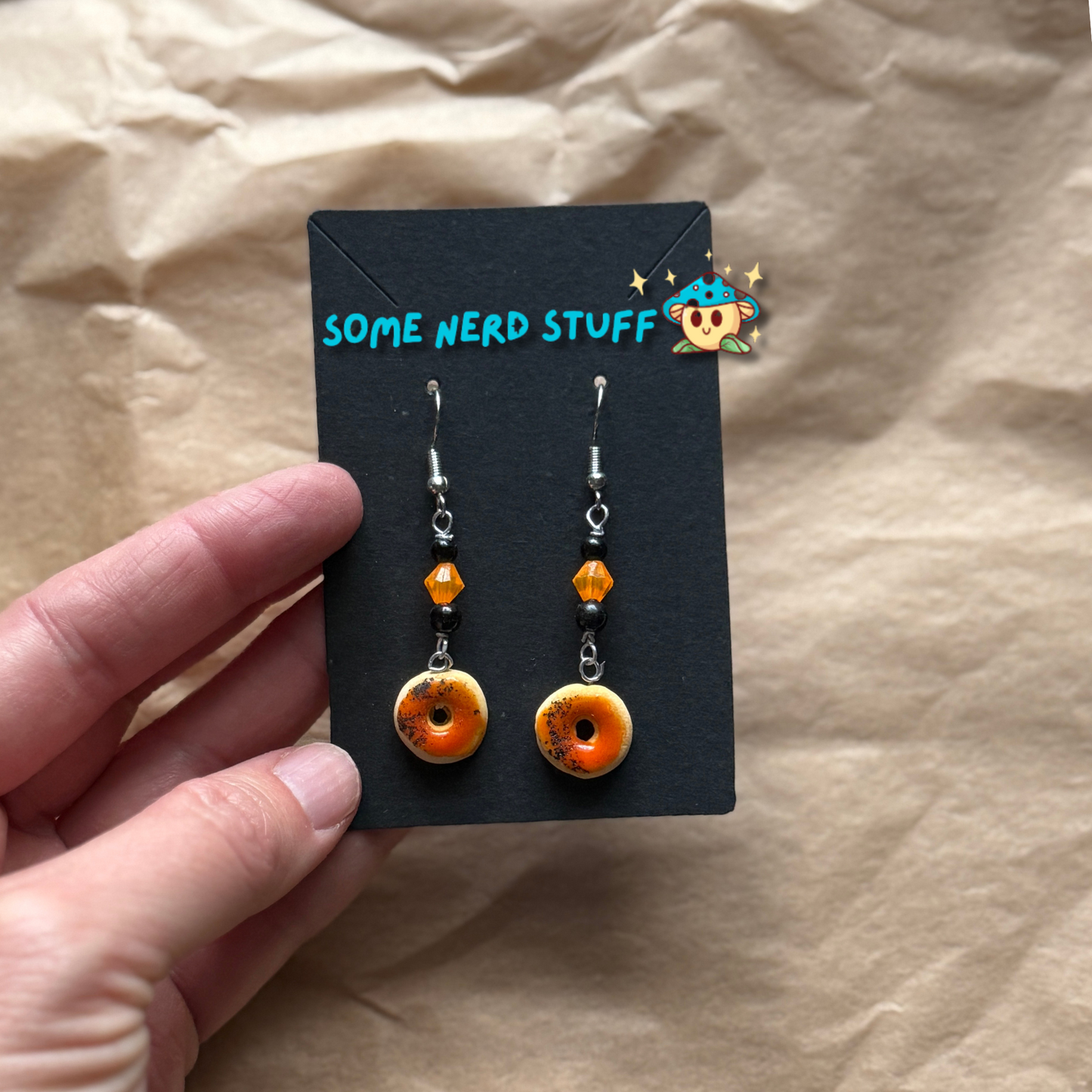 Blood Orange Polymer Clay glazed earring topped with beads shown in hand for size