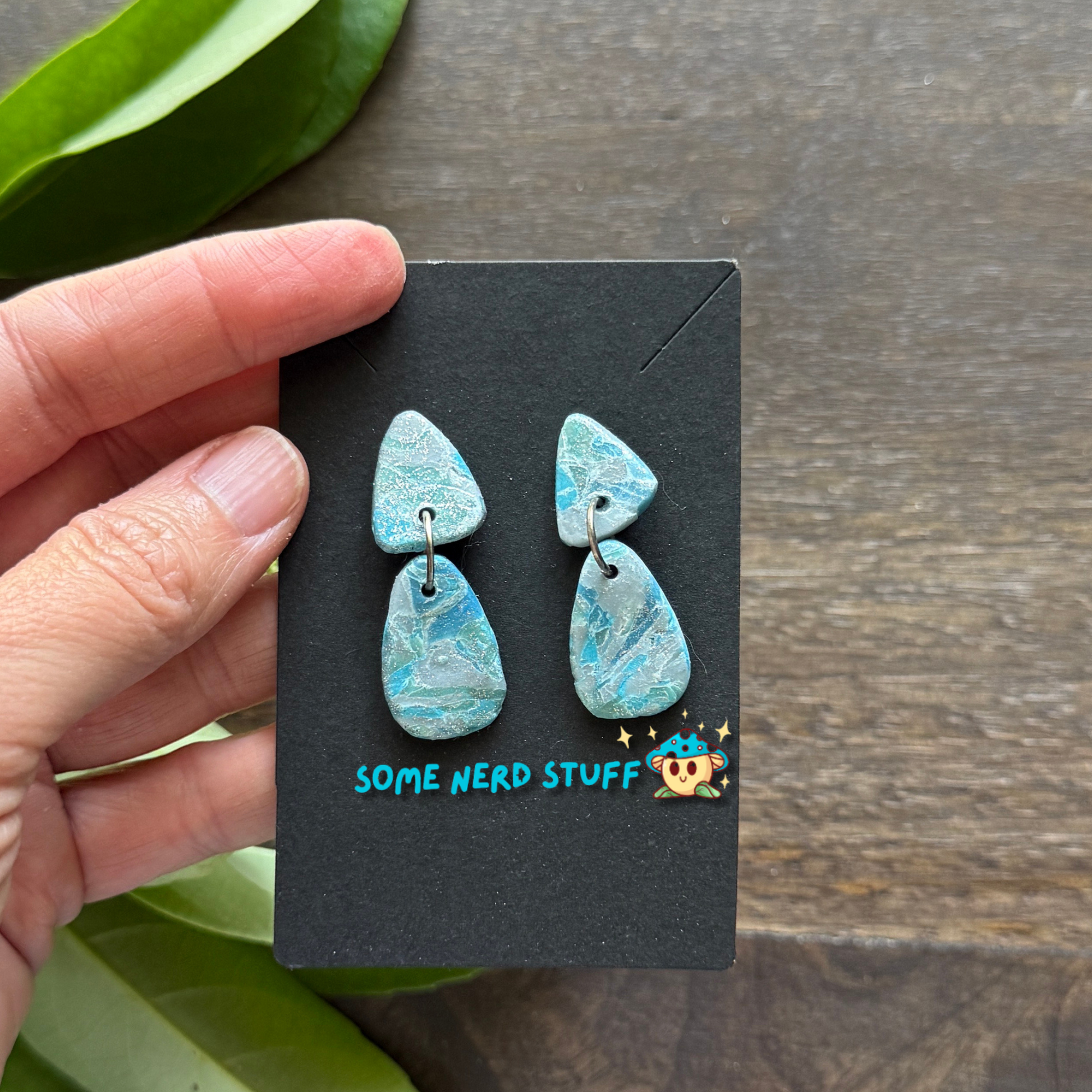 Close up of a hand holding faux polymer clay faux stone earrings from SomeNerdStuff Store