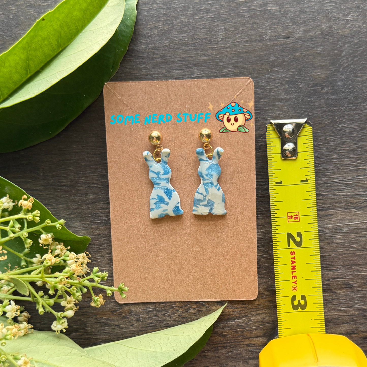 Polymer Clay Earring inspired by white and blue granit stone, shown with measuring tape for size.