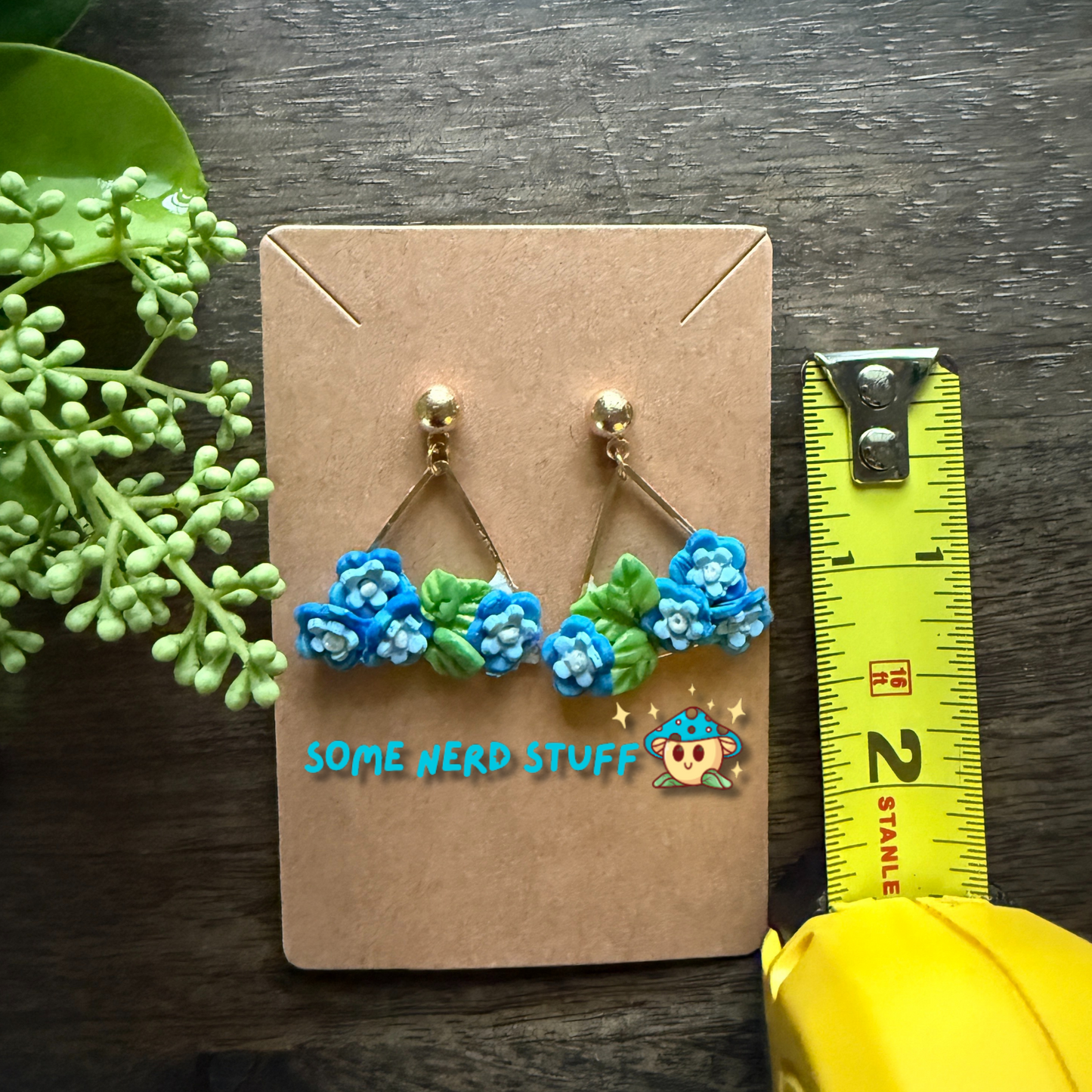 Manga Frieren: Beyond Journey's End Inspired Blue Moon Flower Polymer clay earrings shown with measuring tape made by SomeNerdStuff
