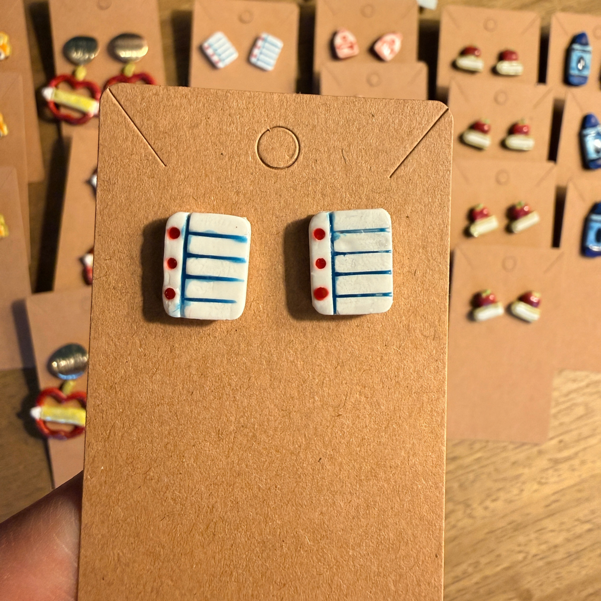 Hand holding a pair of white notebook paper studs with blue lines and red margins.