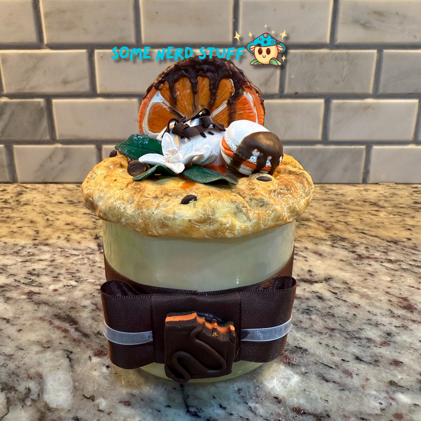 Polymer Clay Stash Jar Topped with faux Orange dipped chocolate, vanilla macaron, jasmine flower, and candies.
