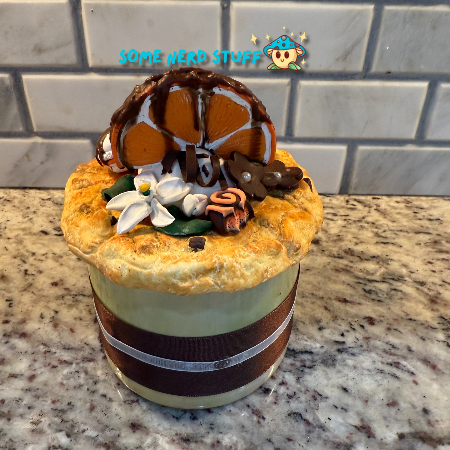 Polymer Clay Stash Jar Topped with faux Orange dipped chocolate, vanilla macaron, jasmine flower, and candies.