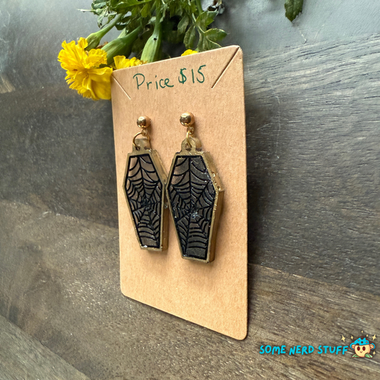 Black coffin-shaped earrings on a beige card handmade with love from somenerdstuff