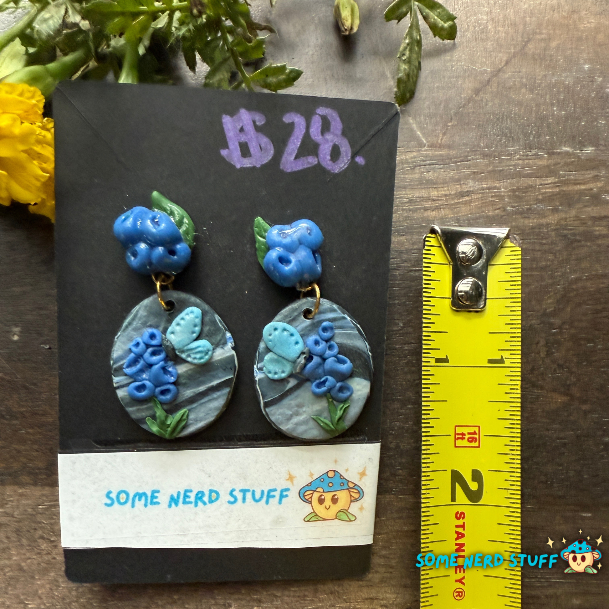 Pair of blue floral earrings on a 'Some Nerd Stuff' branded card with a ruler for scale.