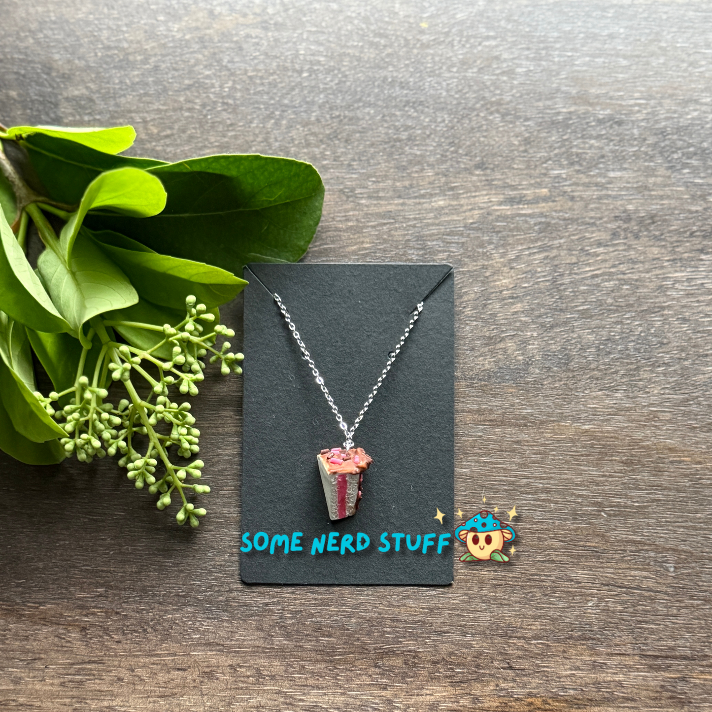Cholcoale Ganache Cake Charm made out of polymer clay and necklace showing cake layers vanilla and strawberry made by SomeNerdStuff