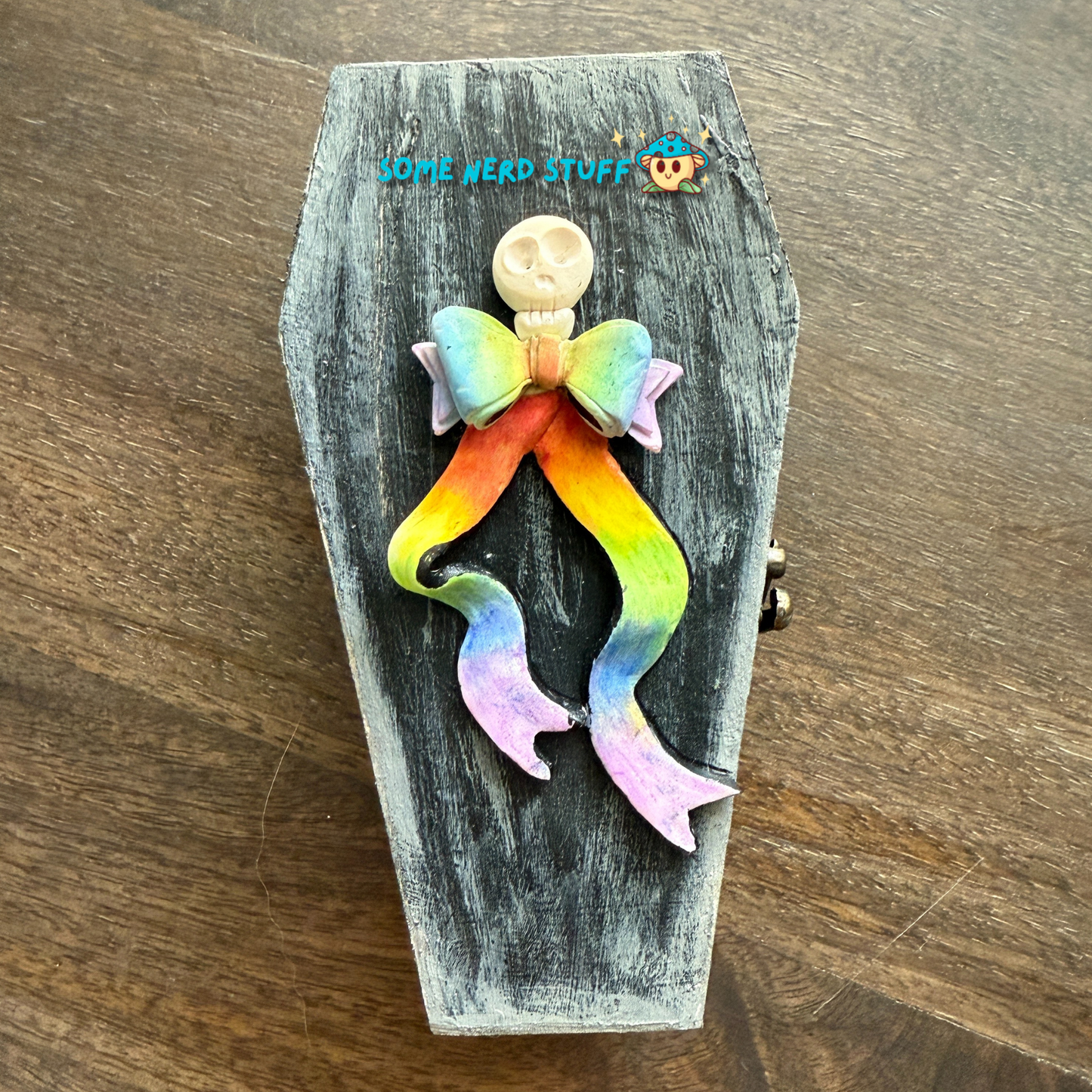 Wooden craft coffin decorated with rainbow polymer clay topped clay skull