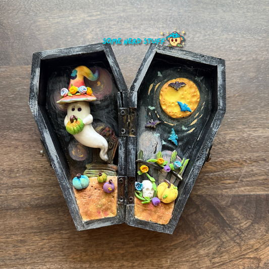 Wooden craft coffin decorated with  polymer clay ghost topped with a patchwork witch hat, mini pumpkins, tombstone, bats over the moon, and so much more.