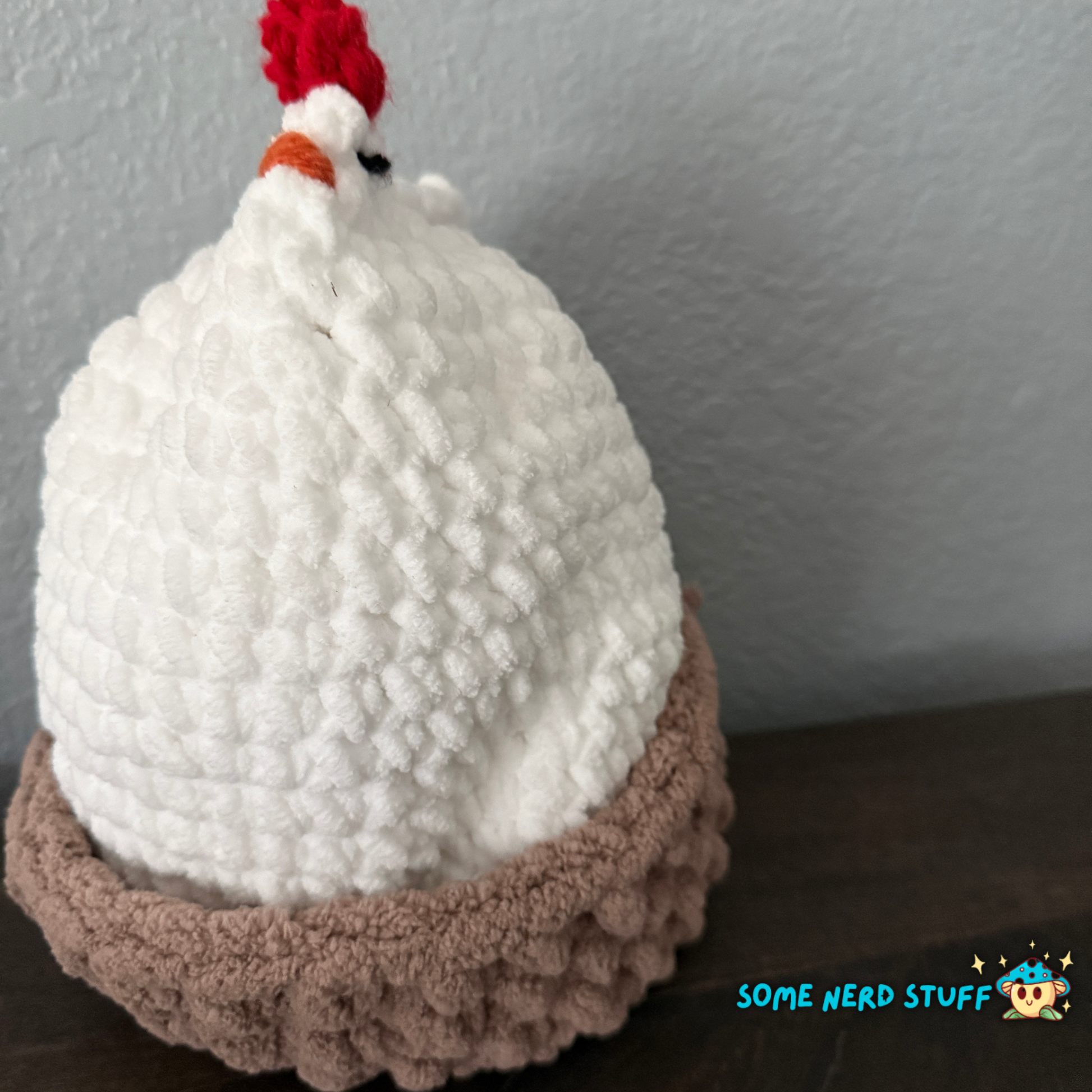 Crocheted chicken DIxie with baby cluck chick and holds a fun glitter egg all sitting on a ultra soft crocheted nest sold by SomeNerdStuff