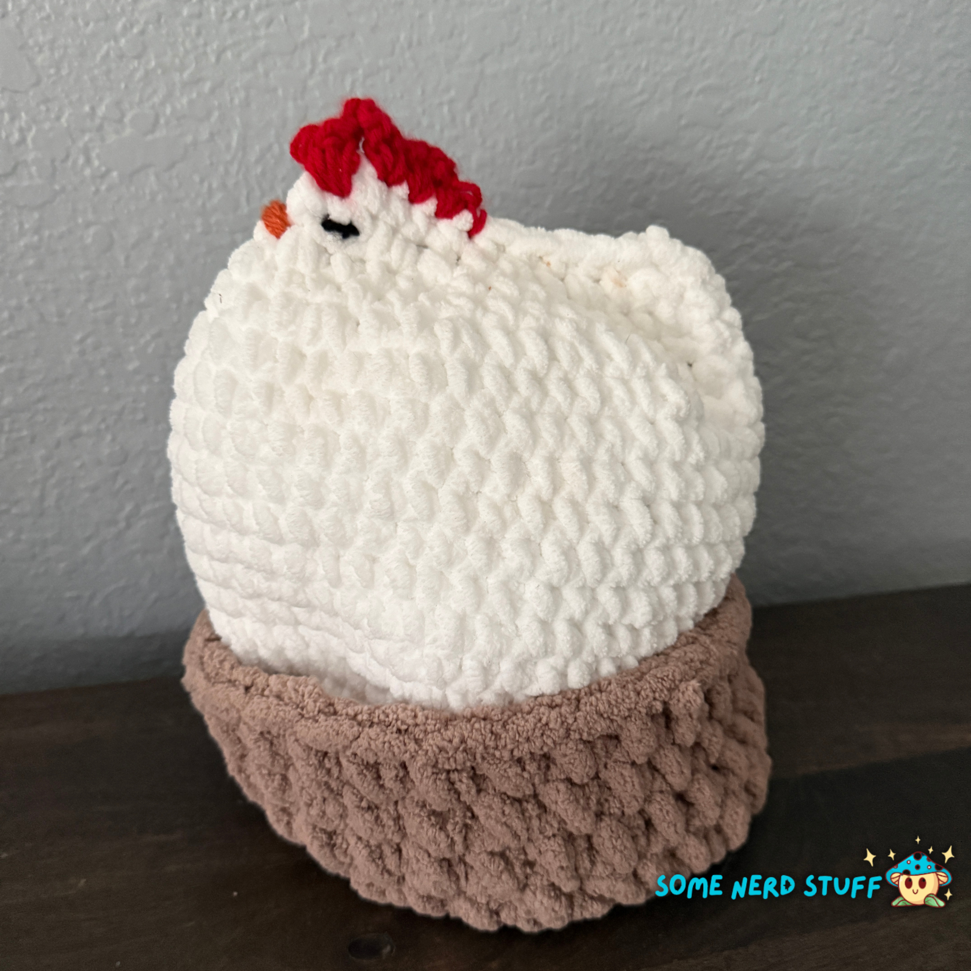 Crocheted chicken DIxie with baby cluck chick and holds a fun glitter egg all sitting on a ultra soft crocheted nest sold by SomeNerdStuff