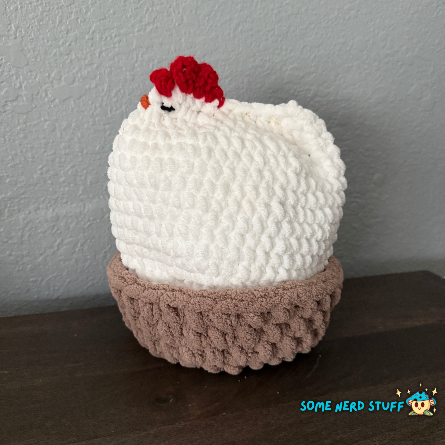 Crocheted chicken DIxie with baby cluck chick and holds a fun glitter egg all sitting on a ultra soft crocheted nest sold by SomeNerdStuff