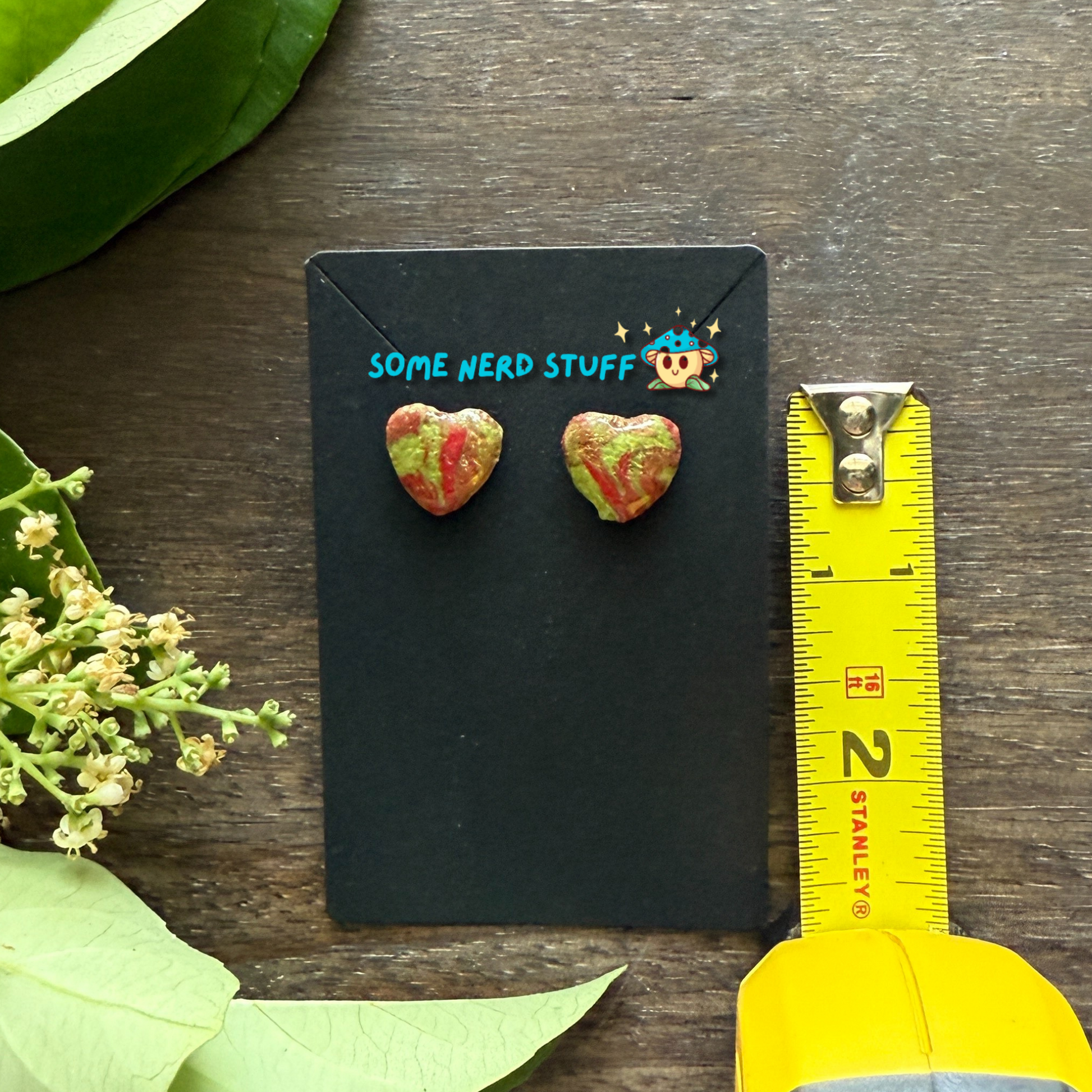 Polymer Clay swirl red and green heart earrings shown with measuring tape by SomeNerdStuff