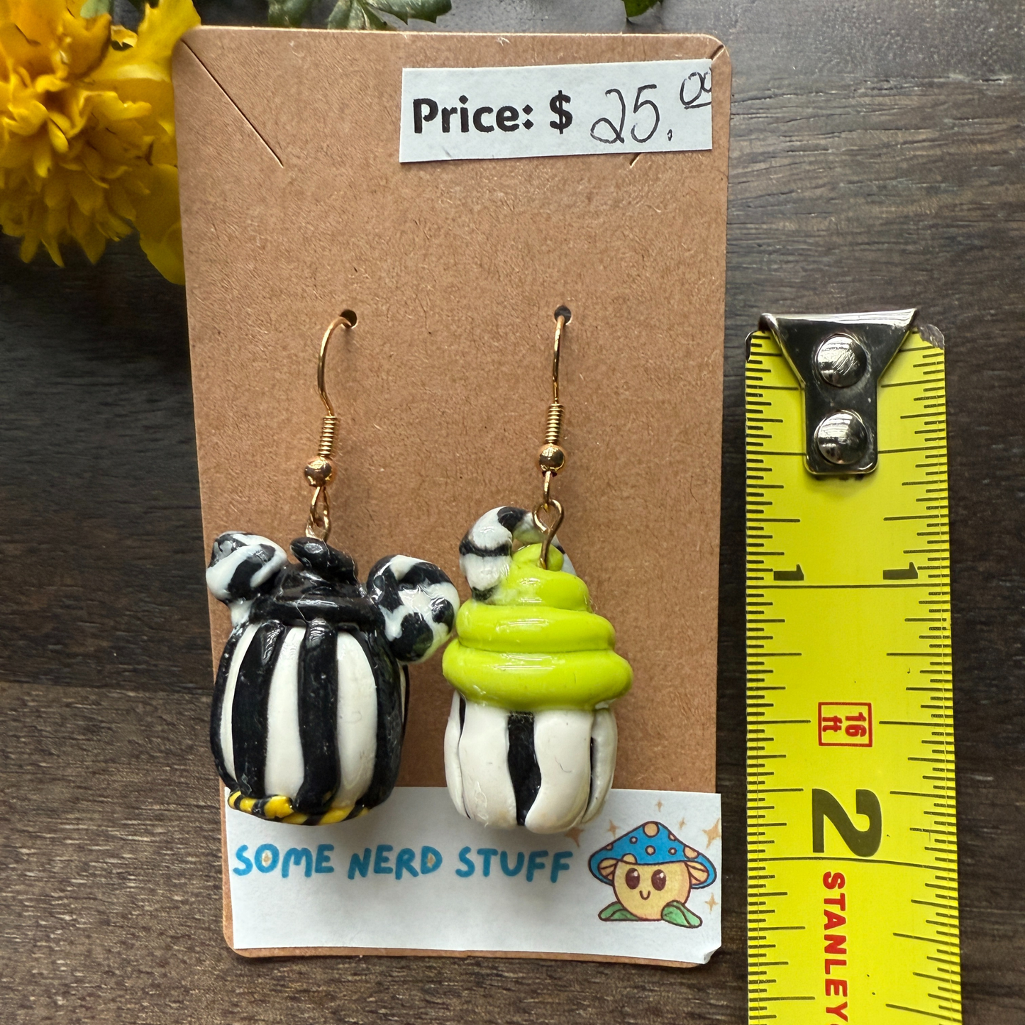Pair of Nightmare before Christmas themed polymer clay earrings sold by SomeNerdStuff showing measuring tape for size