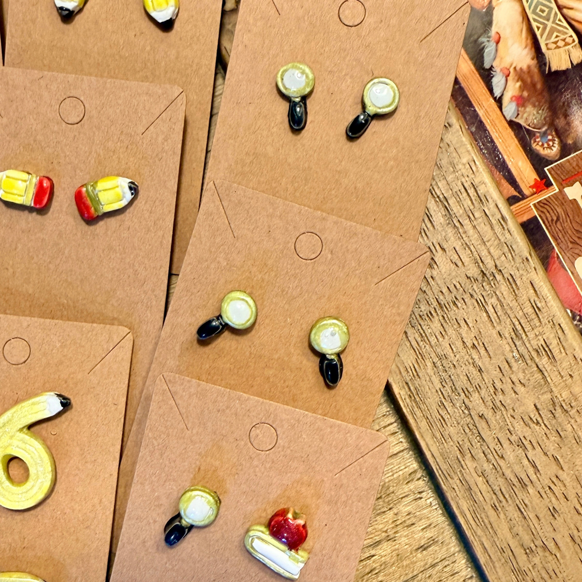 Several pairs of miniature magnifying glass stud earrings with gold-tone rims and black handles.