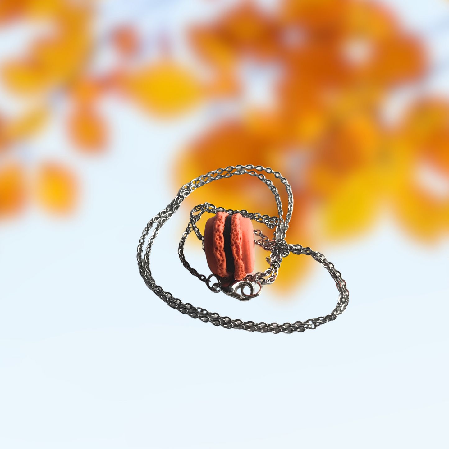 Orange and Black Macaron Polymer Clay Charm and Necklace in hand to show size made by SomeNerd Stuff