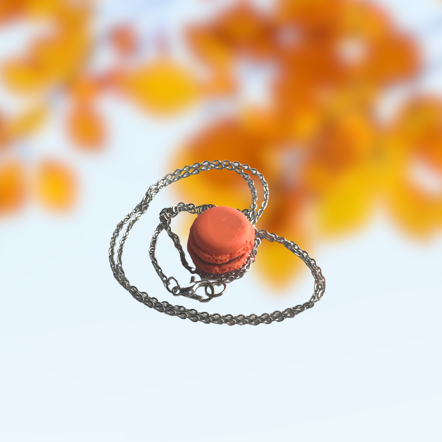 Orange and Black Macaron Polymer Clay Charm and Necklace in hand to show size made by SomeNerd Stuff