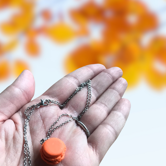 Orange and Black Macaron Polymer Clay Charm and Necklace in hand to show size made by SomeNerd Stuff