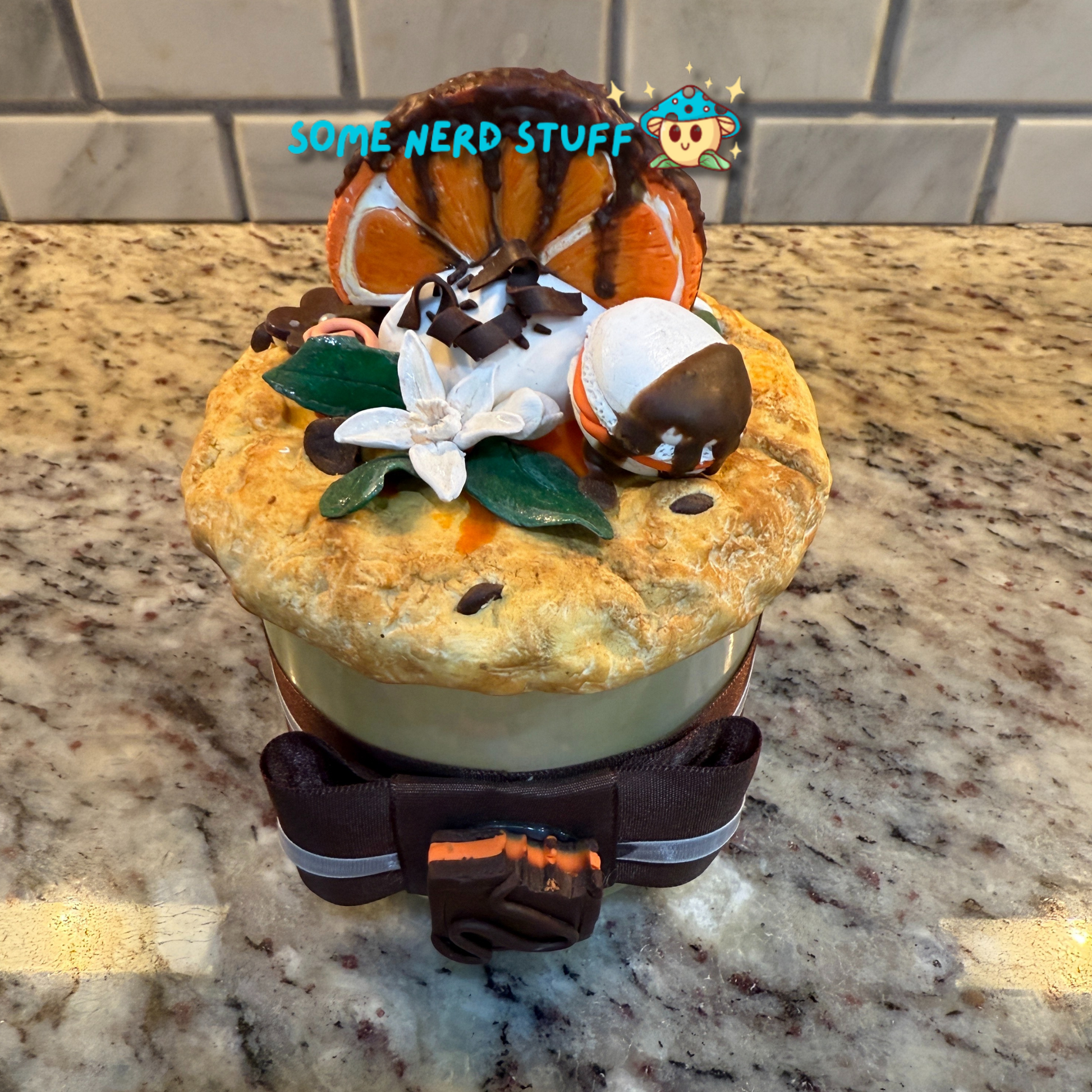 Polymer Clay Stash Jar Topped with faux Orange dipped chocolate, vanilla macaron, jasmine flower, and candies top view of jar