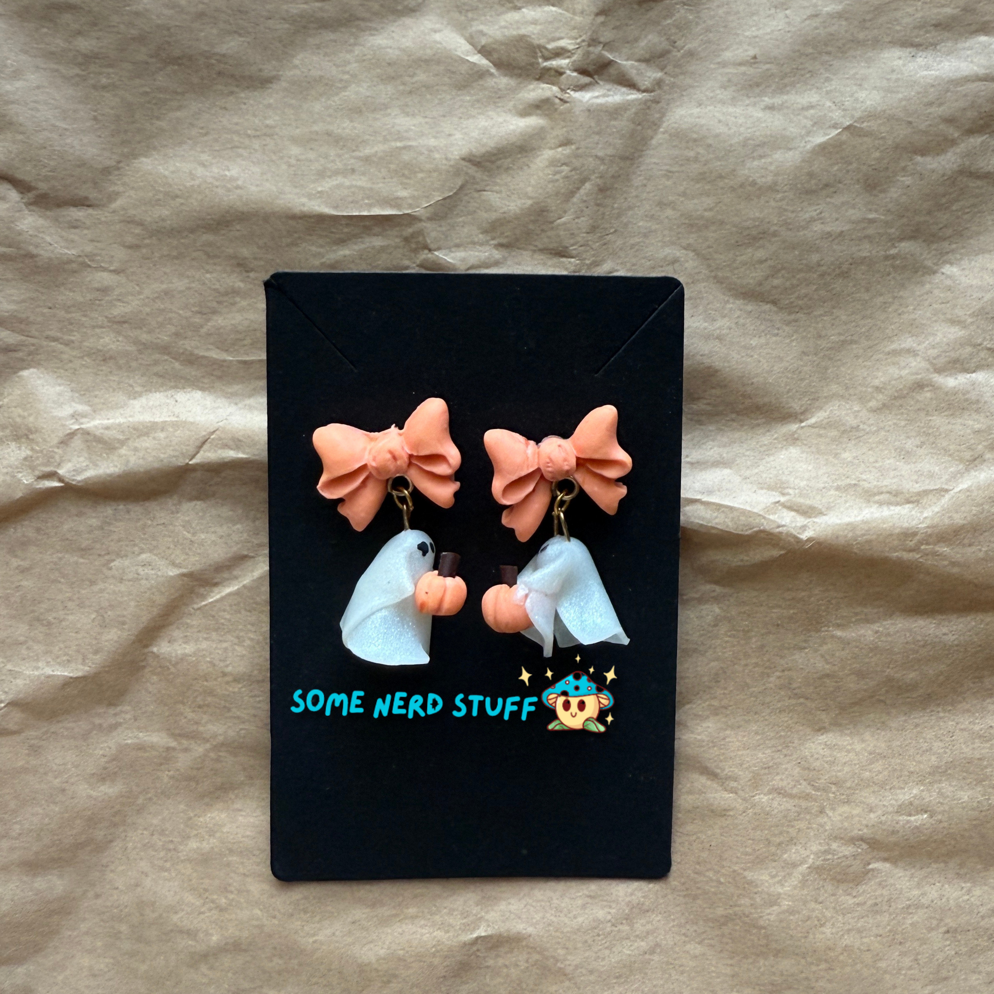 Polymer Clay Stud earrings with peach bows, phantoms holding pumpkins side view made by SomeNerdStuff