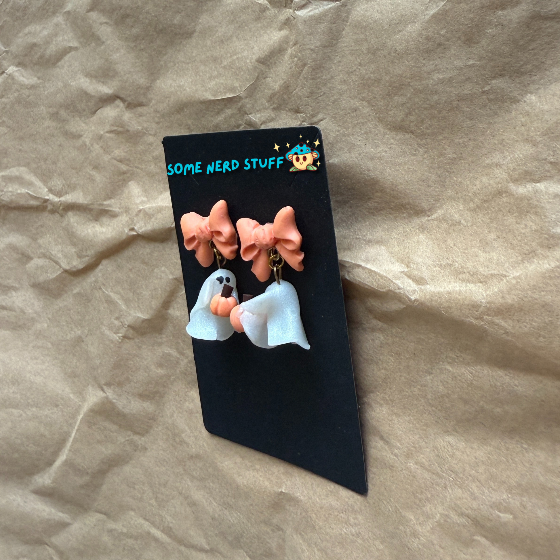 Polymer Clay Stud earrings with peach bows, phantoms holding pumpkins side view made by SomeNerdStuff