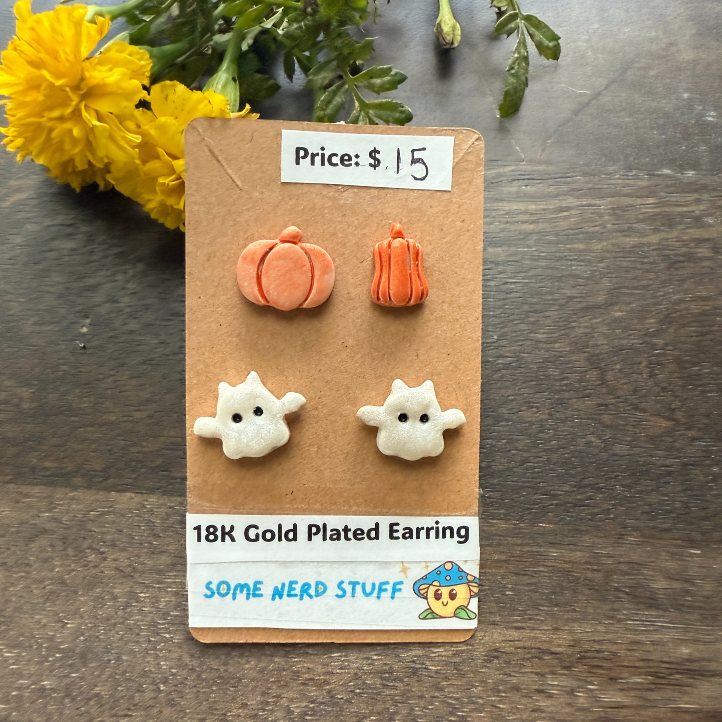 Pair of 18K gold-plated ghost earrings on a cardboard backing with price tag and branding label.