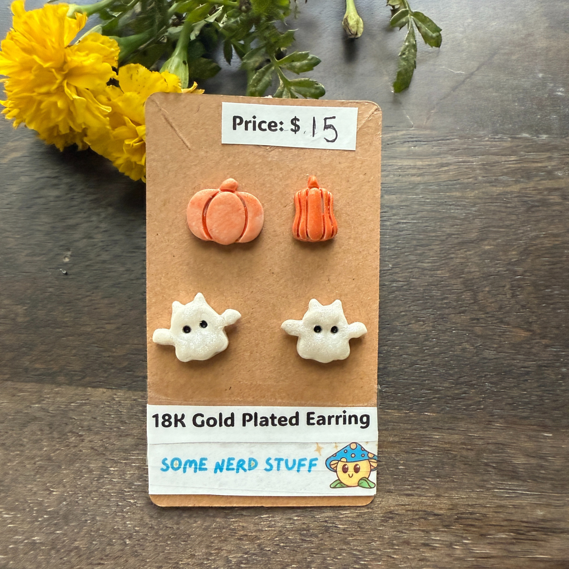 Pair of 18K gold-plated ghost earrings on a cardboard backing with price tag and branding label.