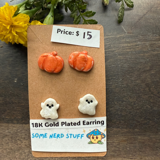 Halloween-themed earrings on a cardboard backing with a price tag, on a wooden surface featuring pumpkins and happy ghosts 18k gold plated earrings.