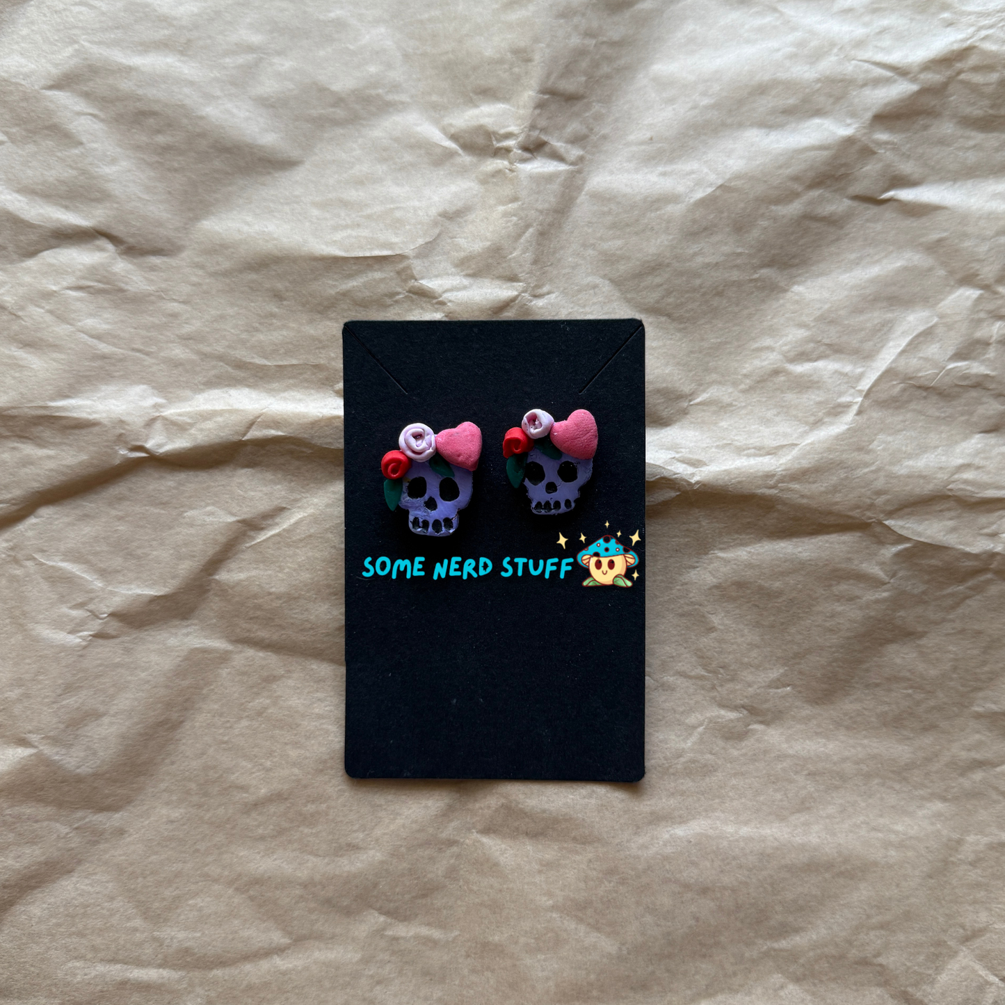 Polymer Clay Stud earrings with purple skulls, pink and red roses, with pink hearts front view made by SomeNerdStuff