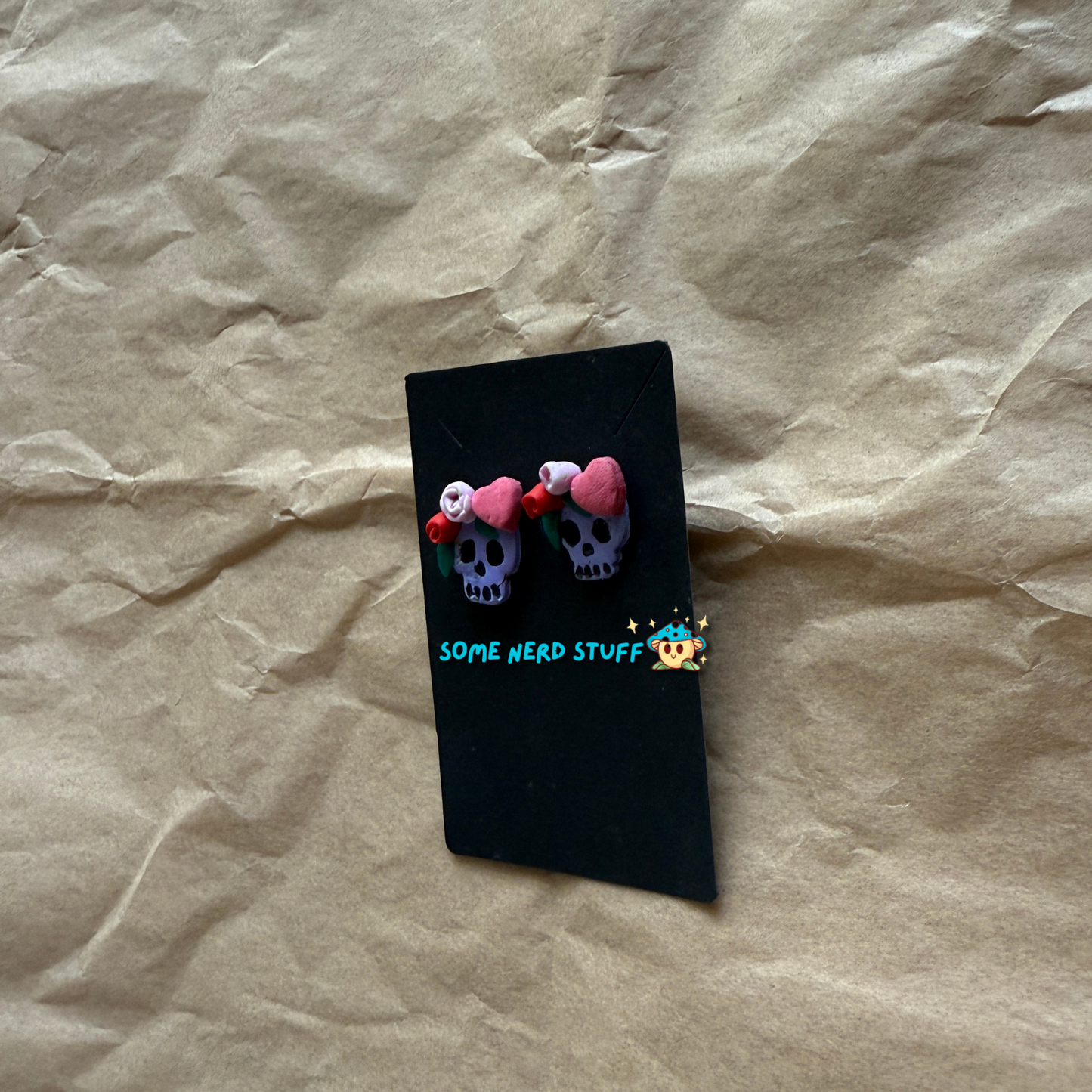 Polymer Clay Stud earrings with purple skulls, pink and red roses, with pink hearts side view made by SomeNerdStuff