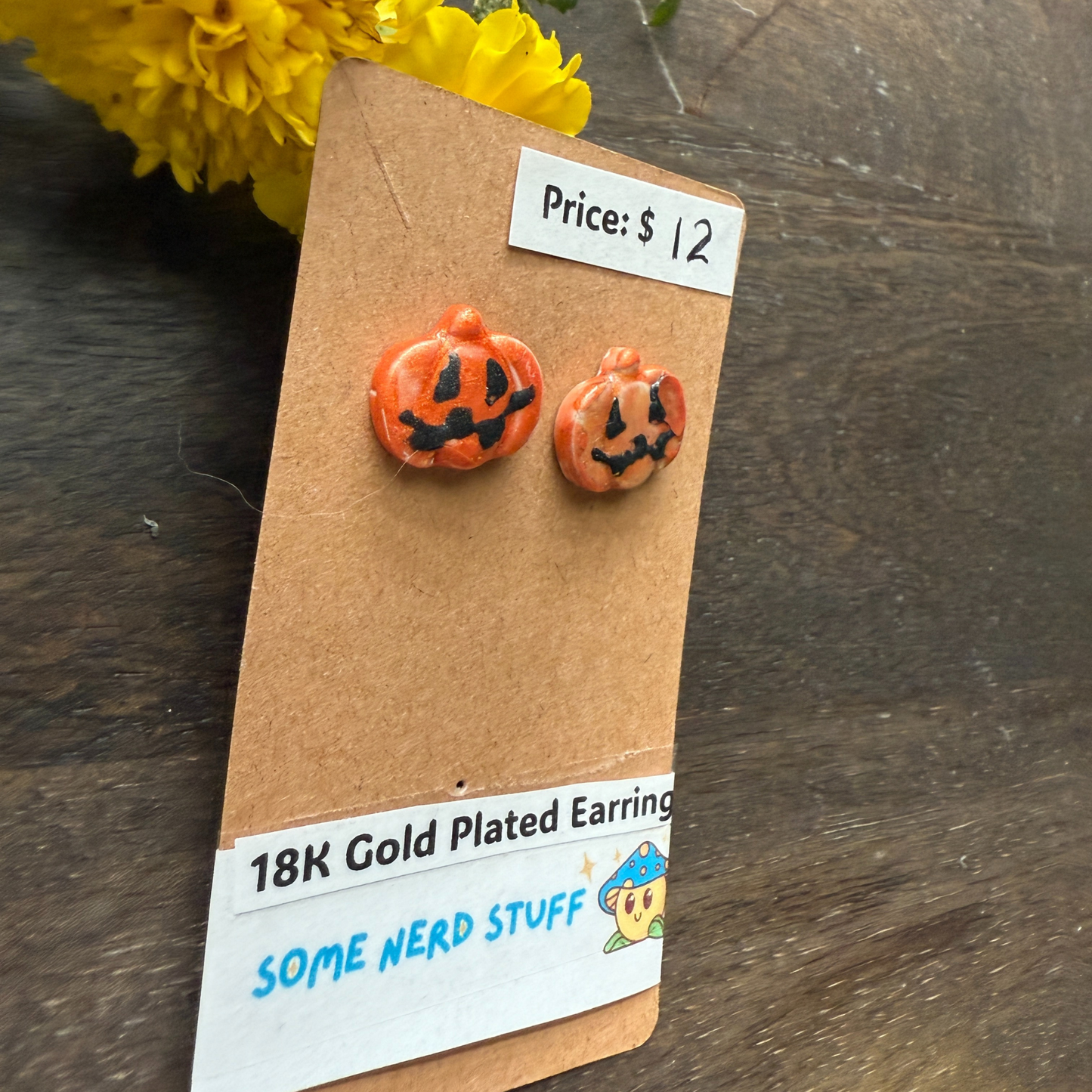 Halloween-themed pumpkin earrings on a 'Some Nerd Stuff' branded card with price tag.
