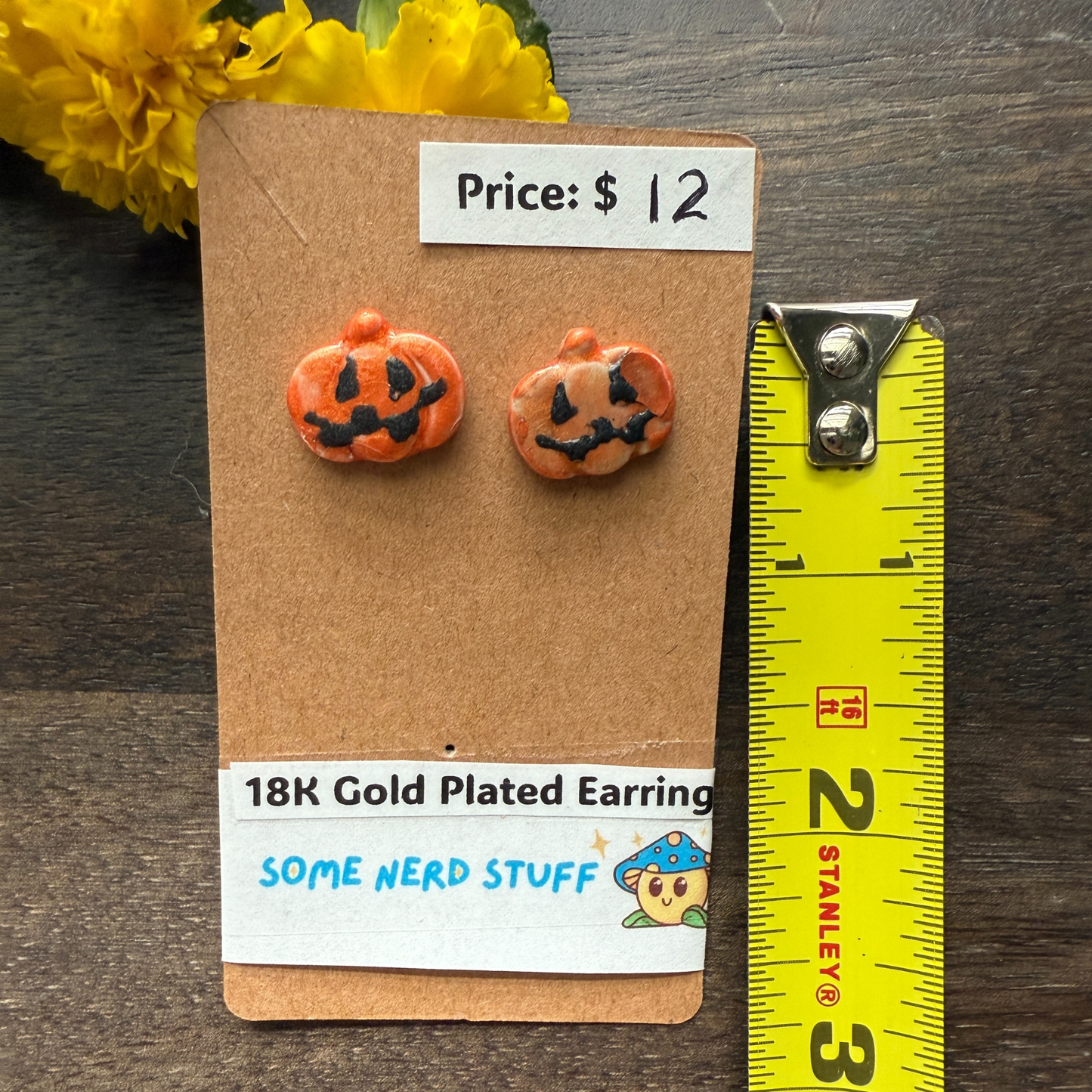 Halloween-themed pumpkin earrings on a cardboard backing with price and 18k plated earrings