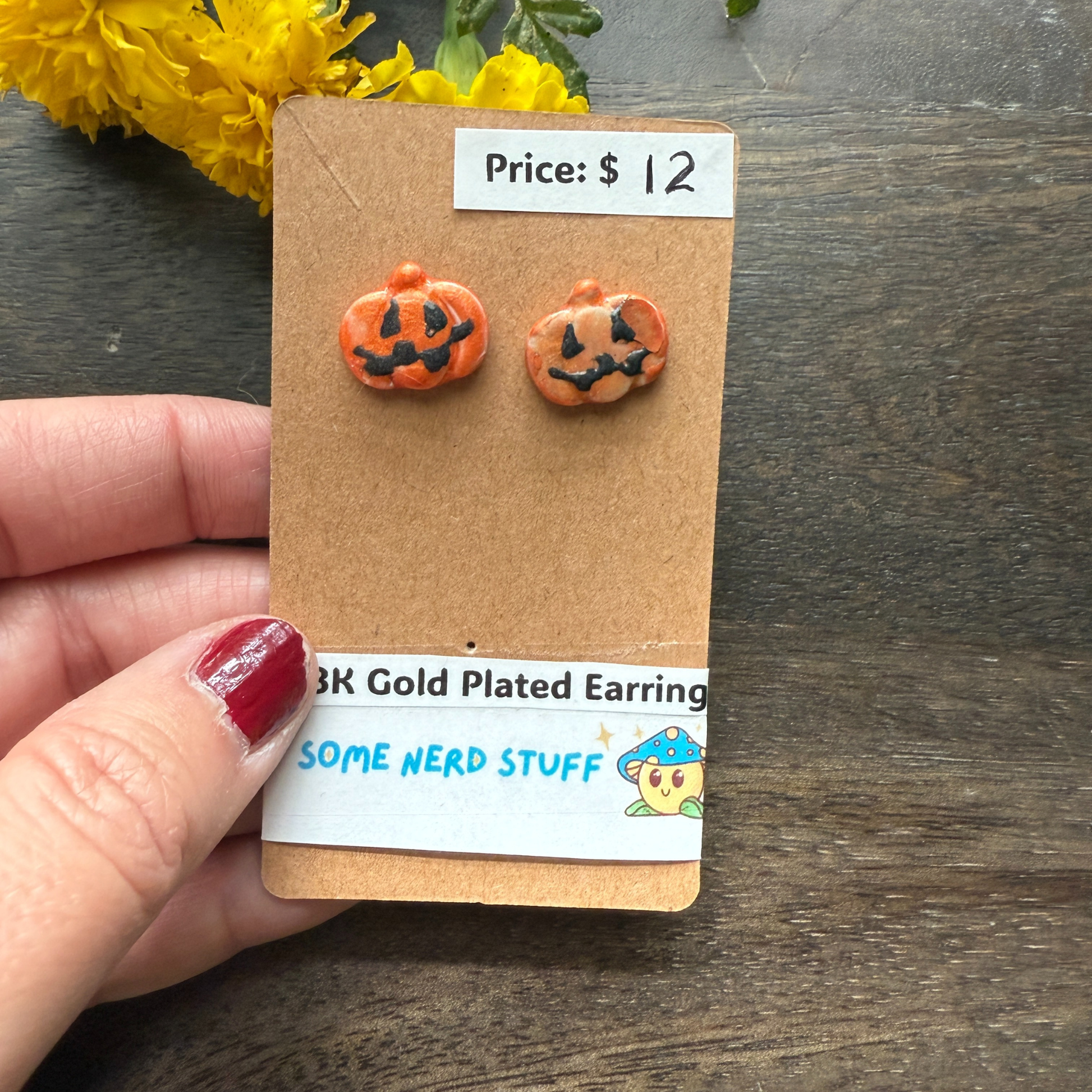 Halloween-themed pumpkin earrings on a cardboard backing with price and 18k plated earrings