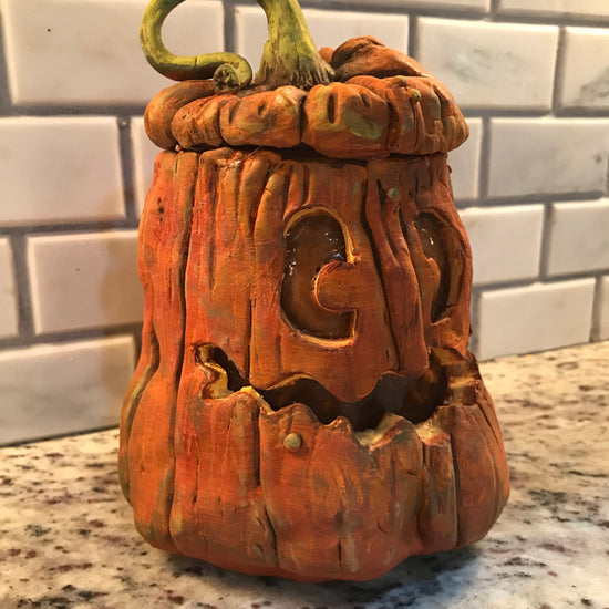 Pumpkin made out of polymer clay to create a jar, lid topped with green vine and smiling face.