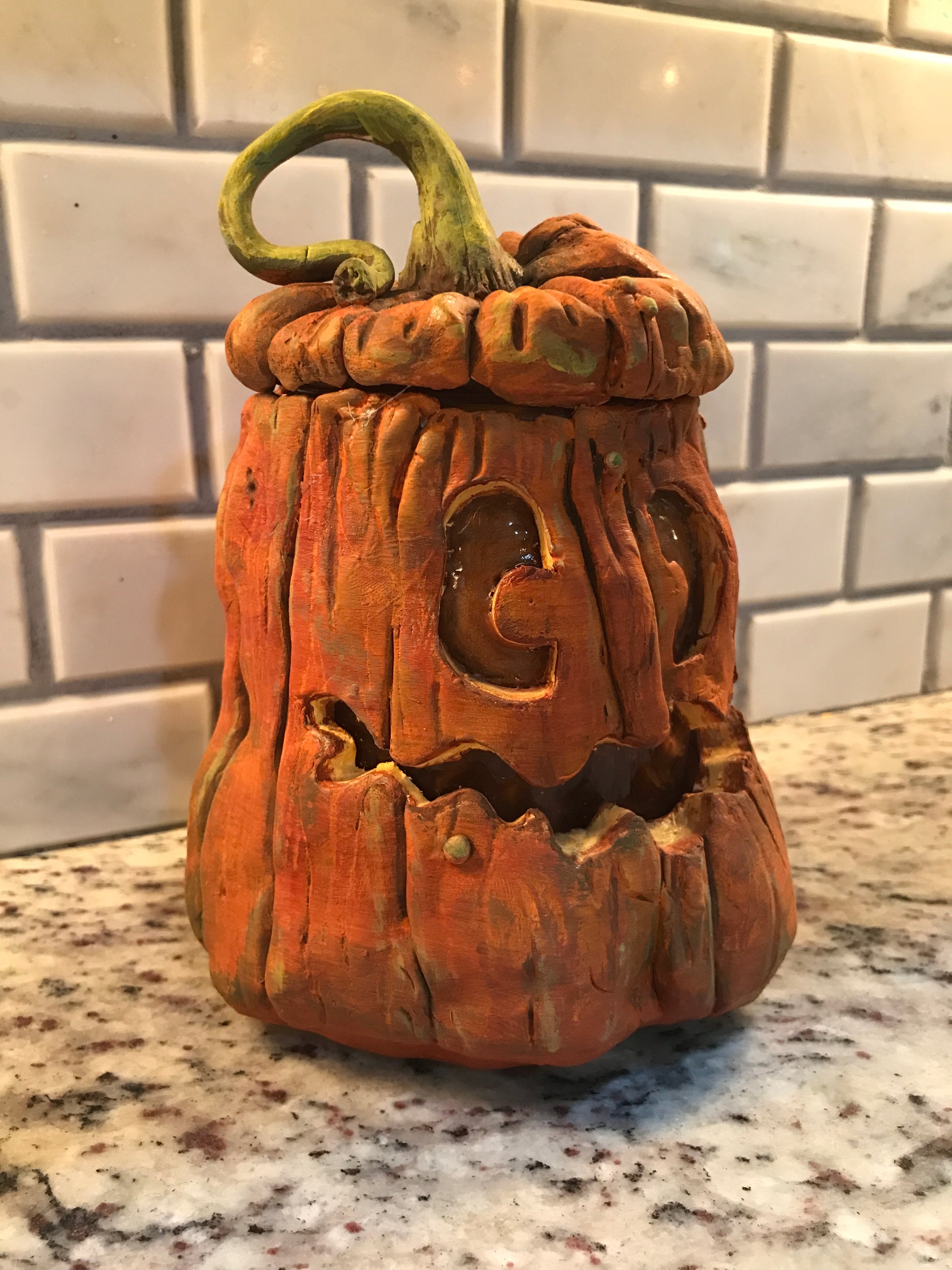 Pumpkin made out of polymer clay to create a jar, lid topped with green vine and smiling face.