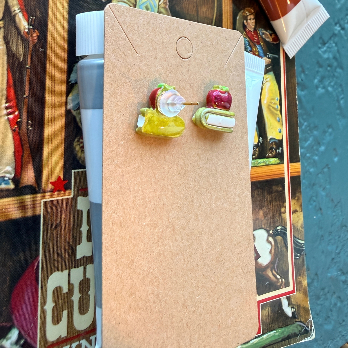 Apple and book stud earrings shown from the front and back with their posts and backings.
